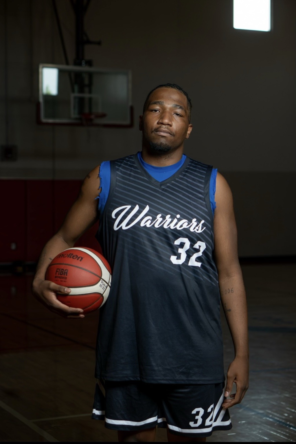 Elijah McNeil holding a basketball in his number 32 Colorado Warriors uniform