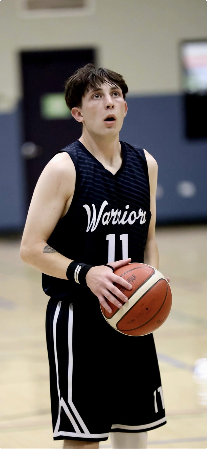 Ethan Stevenson holding a basketball in his number 11 Colorado Warriors uniform